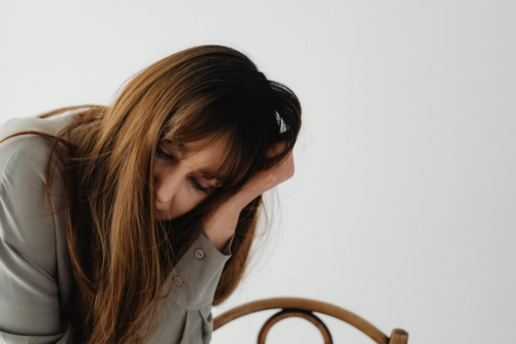 Woman in professional attire bowed forward with head in hand, capturing the exhaustion of how to recover from burnout at work